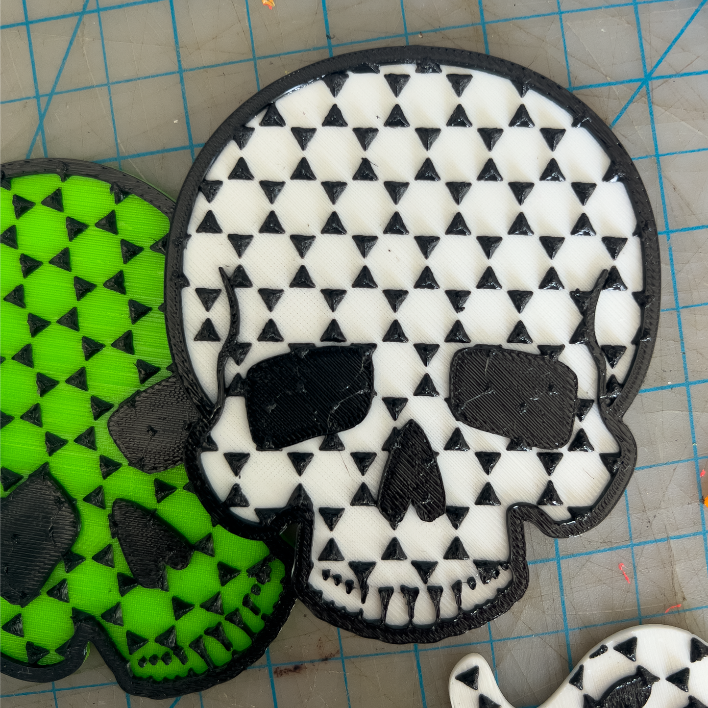 Skull-shaped foot grips with black and white pattern on a green and black checkered background