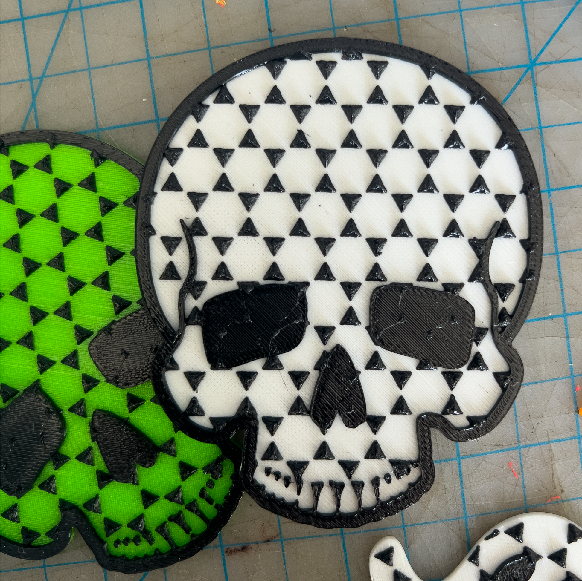 Skull-shaped foot grips with black and white pattern on a green and black checkered background